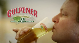 Rij Gulpener bierflessen op een lopende band in een productieomgeving.
