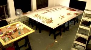 Een tafel bedekt met schaduwkunst gemaakt van gestapelde koekjes naast tekst in het midden.