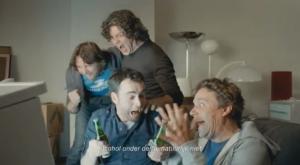 Een groep mannen op een bank kijkt verbaasd naar een koelkast die op robotschoenen staat.