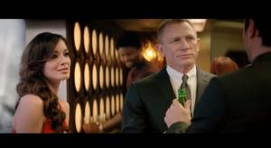 Twee Heineken bierflessen op een bar naast een persoon in een rode jurk.