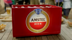 Man met krat bier bij tuinfeest met drie zittende mensen aan tafel.